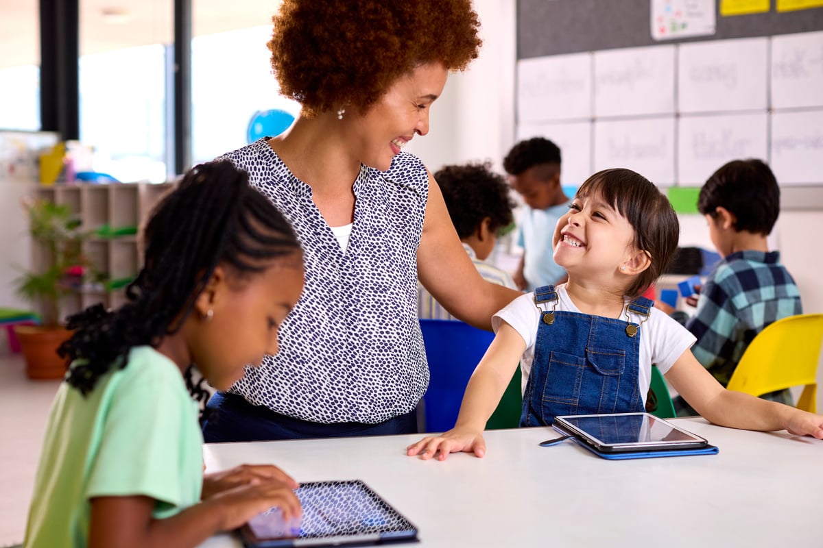 Female Teacher with Multi-Cultural Elementary School Pupils Using Digital Tablets at School